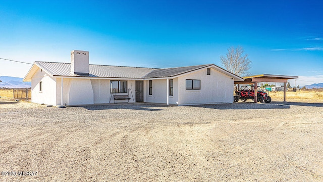 view of front of home featuring a chimney, metal roof, and gravel driveway