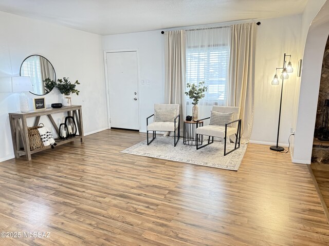 living area with baseboards, arched walkways, and wood finished floors