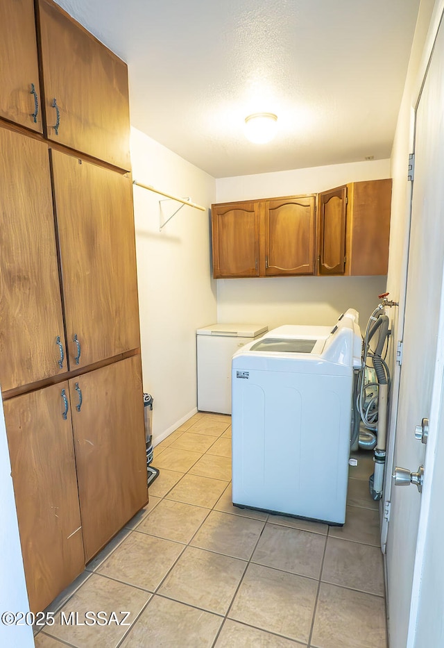laundry area with light tile patterned floors, independent washer and dryer, baseboards, and cabinet space