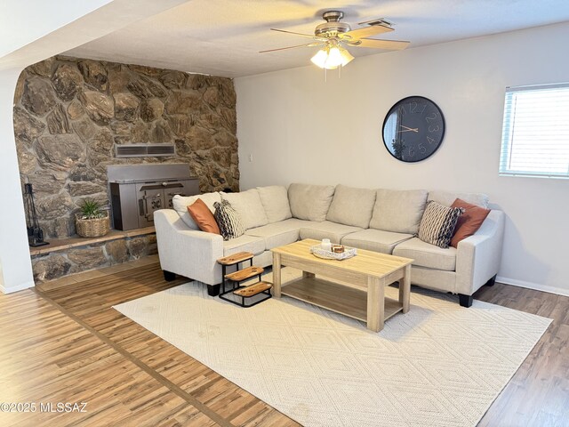 living area with baseboards, a ceiling fan, and wood finished floors