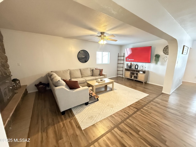 living area featuring a ceiling fan, baseboards, and wood finished floors