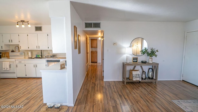 kitchen featuring visible vents, stainless steel dishwasher, white electric range, and wood finished floors