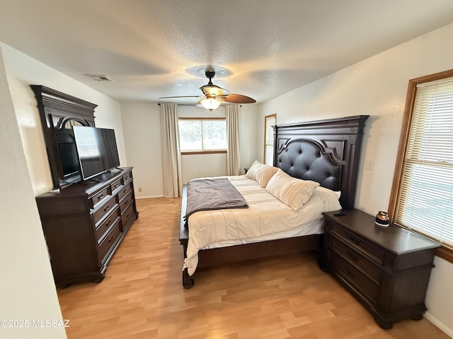 bedroom with visible vents, baseboards, a ceiling fan, and light wood finished floors