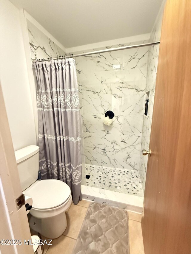 bathroom with toilet, a shower stall, and tile patterned flooring