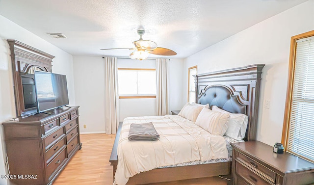 bedroom featuring light wood-style floors, baseboards, a ceiling fan, and visible vents