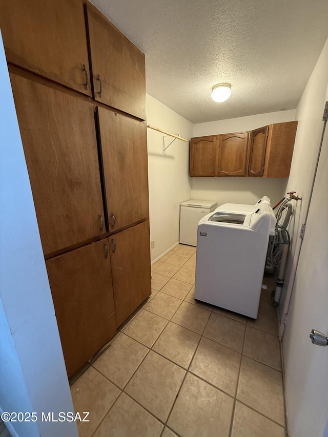 laundry area with washing machine and dryer, light tile patterned floors, cabinet space, and a textured ceiling