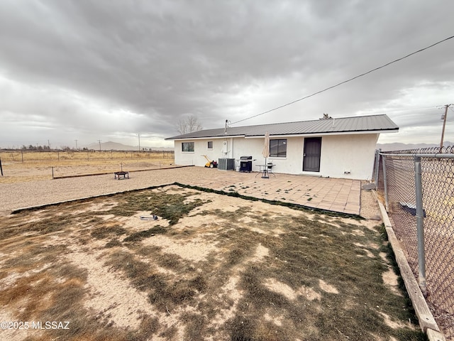 back of property featuring stucco siding, a patio, fence, metal roof, and central AC unit