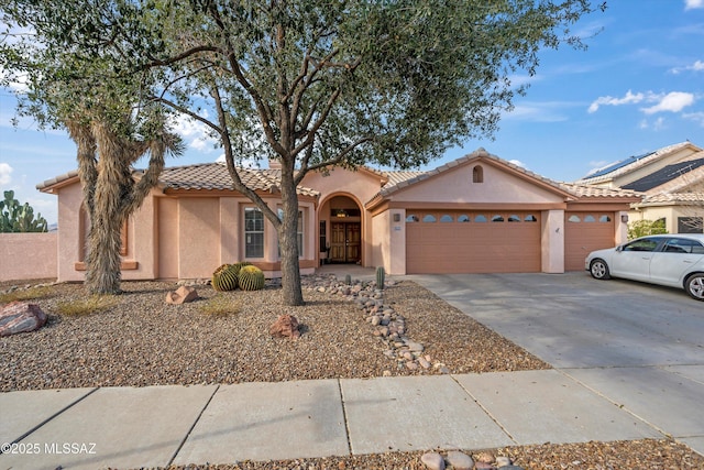 view of front of house featuring a garage, a tile roof, concrete driveway, and stucco siding