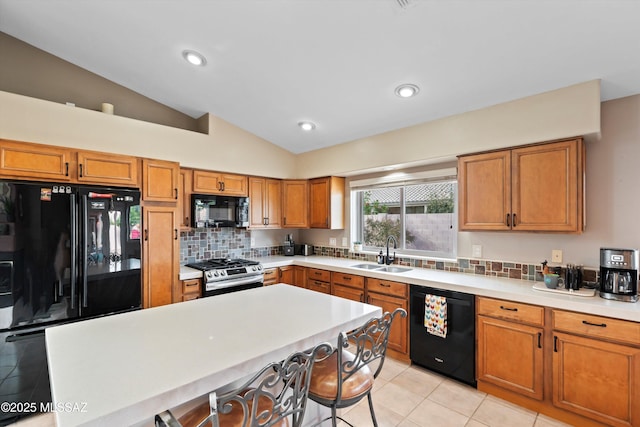 kitchen featuring brown cabinets, a kitchen breakfast bar, light tile patterned flooring, black appliances, and a sink