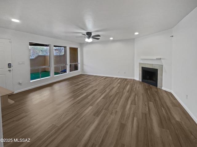 unfurnished living room with baseboards, wood finished floors, and a tile fireplace