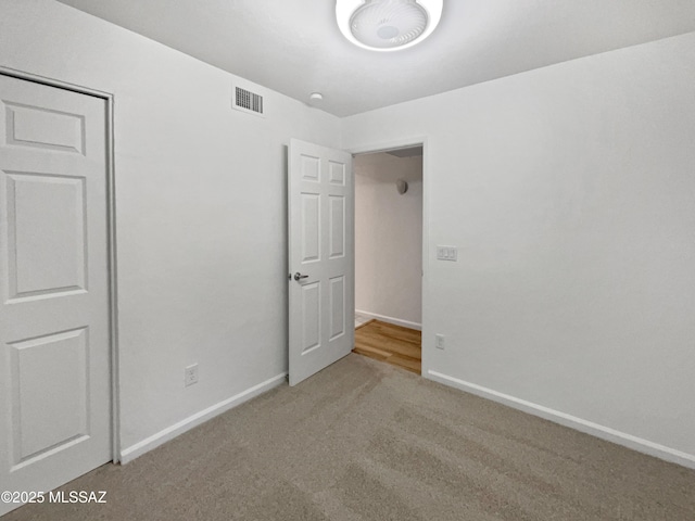 unfurnished bedroom with visible vents, carpet, and baseboards