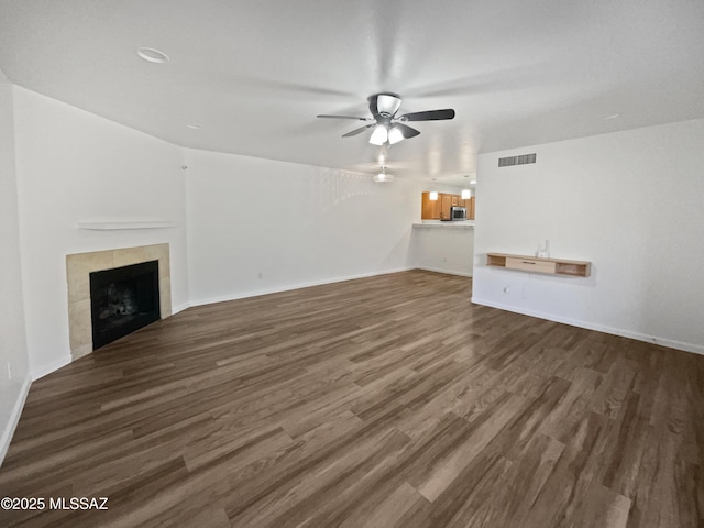 unfurnished living room with wood finished floors, baseboards, visible vents, a fireplace, and ceiling fan