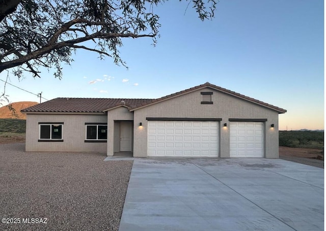 ranch-style house featuring a tile roof, an attached garage, driveway, and stucco siding