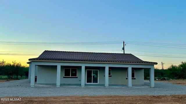 view of front of property featuring covered porch, a tiled roof, and stucco siding