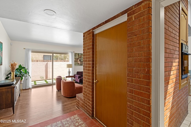 corridor featuring a textured ceiling, brick wall, and tile patterned flooring