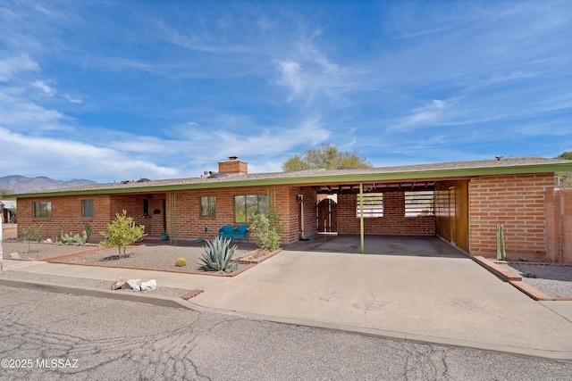 single story home with an attached carport, brick siding, and a chimney
