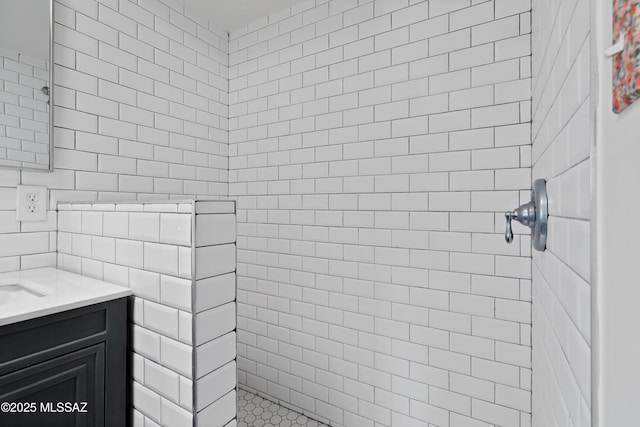 bathroom featuring tiled shower, vanity, and tile walls