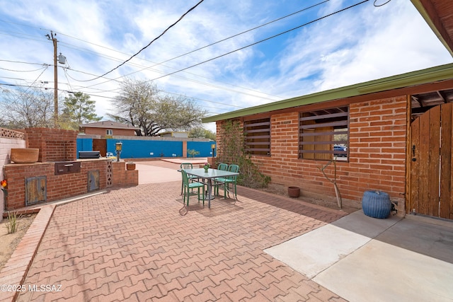 view of patio with outdoor dining space, fence, and area for grilling