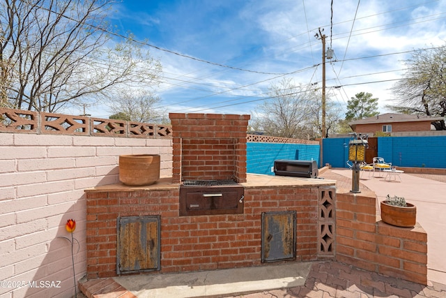 view of patio / terrace with grilling area, an outdoor kitchen, and fence