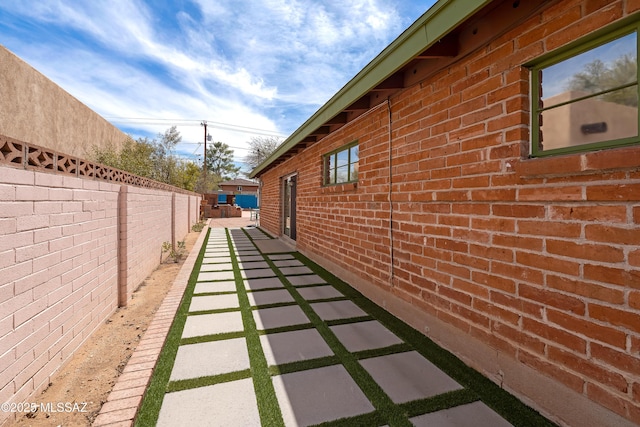 view of side of property featuring brick siding and fence