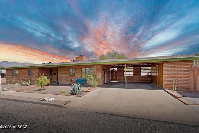 ranch-style house with a carport, a chimney, and brick siding
