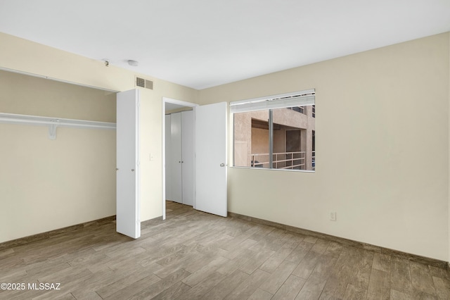 unfurnished bedroom with a closet, visible vents, and wood finished floors