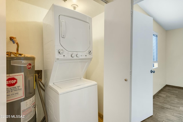 laundry area featuring electric water heater, wood finished floors, stacked washing maching and dryer, baseboards, and laundry area