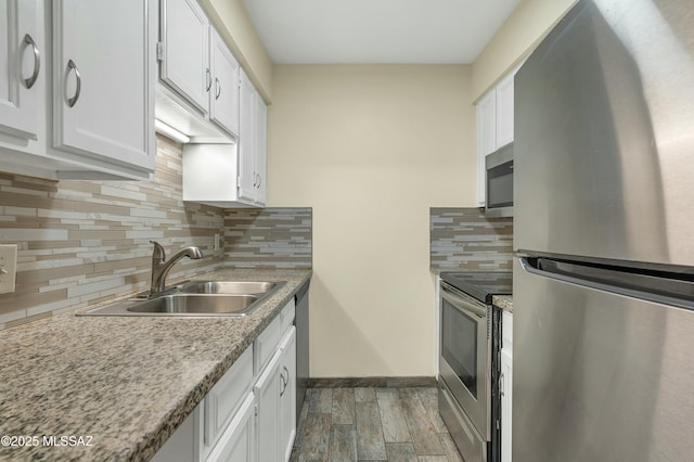 kitchen featuring decorative backsplash, appliances with stainless steel finishes, wood finished floors, white cabinets, and a sink