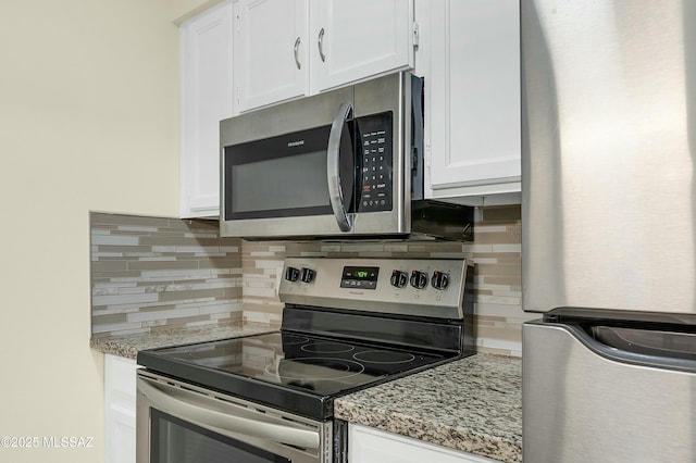 kitchen with decorative backsplash, white cabinetry, stainless steel appliances, and light stone countertops