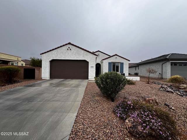 mediterranean / spanish home with stucco siding, driveway, a tile roof, fence, and a garage