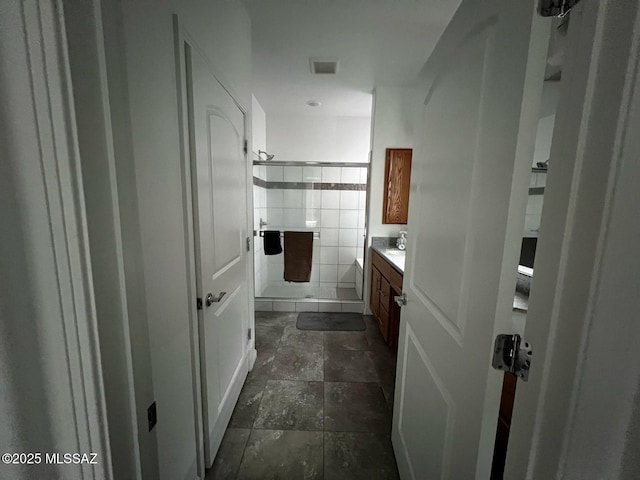 full bath with vanity, stone tile floors, visible vents, a shower stall, and tile walls