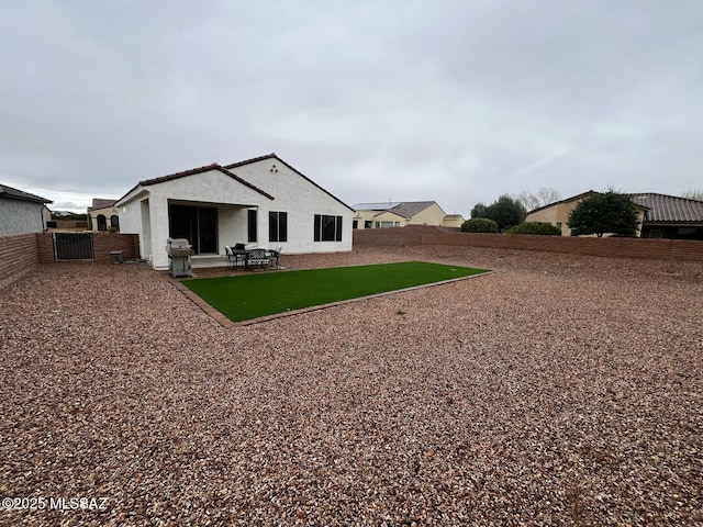 back of house featuring a lawn, a patio, a fenced backyard, and stucco siding