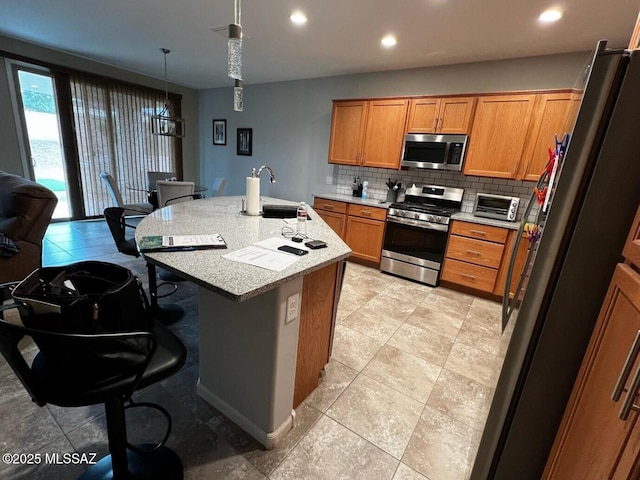 kitchen featuring a sink, decorative backsplash, light countertops, appliances with stainless steel finishes, and brown cabinets