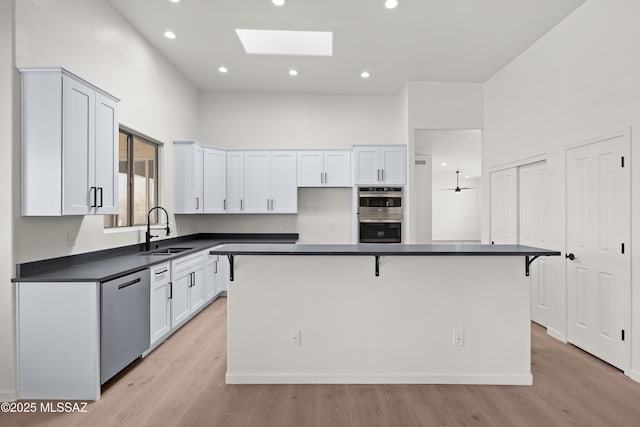 kitchen with a sink, dark countertops, a center island, stainless steel appliances, and a skylight