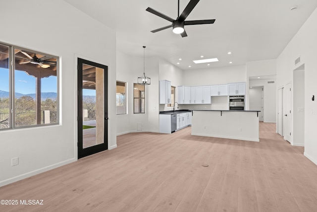 unfurnished living room with visible vents, light wood-type flooring, ceiling fan, and a sink