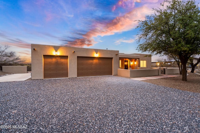 adobe home featuring stucco siding, driveway, and an attached garage