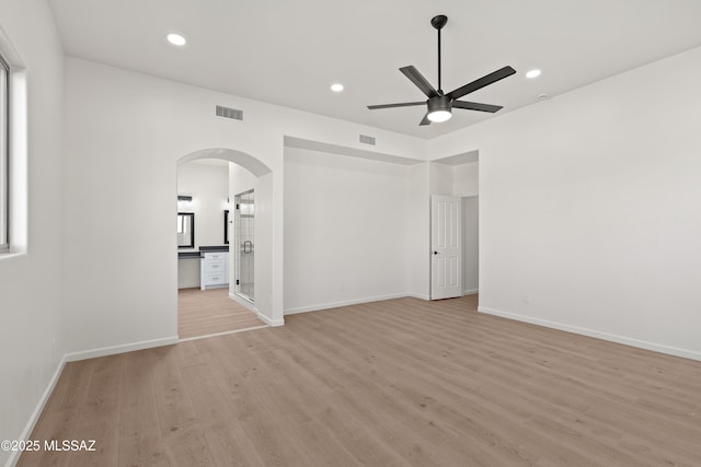 unfurnished room with visible vents, recessed lighting, light wood-style floors, arched walkways, and a ceiling fan