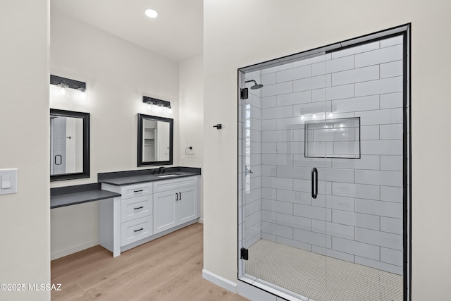 bathroom with baseboards, vanity, wood finished floors, and a shower stall