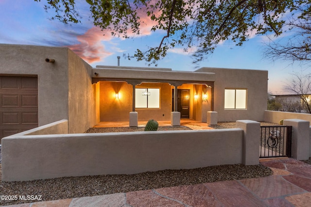 view of front of property featuring a fenced front yard, a garage, stucco siding, and a gate