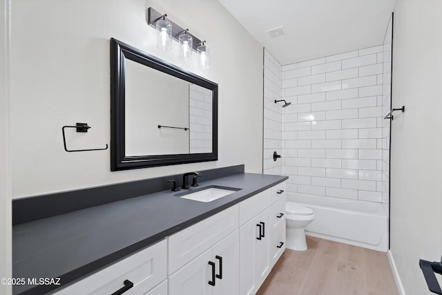 bathroom featuring vanity, washtub / shower combination, wood finished floors, visible vents, and toilet