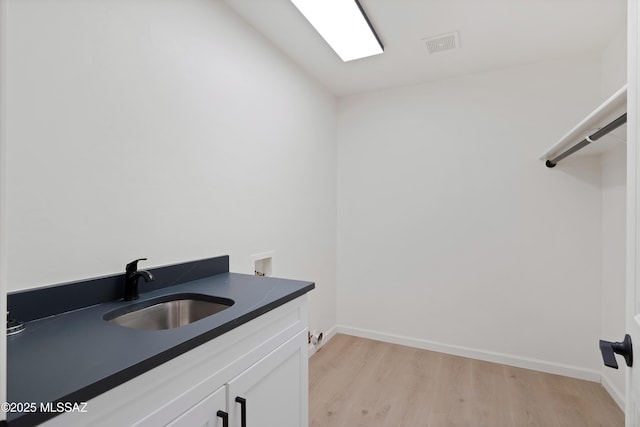 clothes washing area featuring visible vents, light wood-type flooring, washer hookup, cabinet space, and a sink