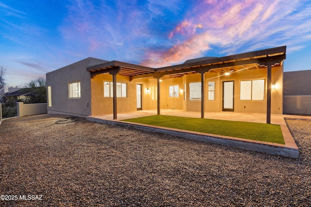 back of property with stucco siding, fence, and a patio area