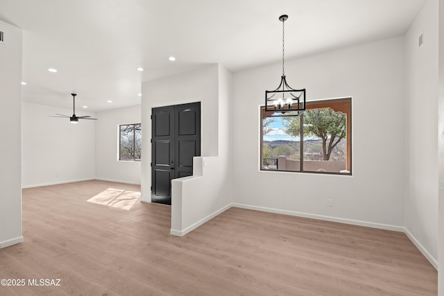 empty room featuring recessed lighting, baseboards, light wood-style flooring, and ceiling fan with notable chandelier