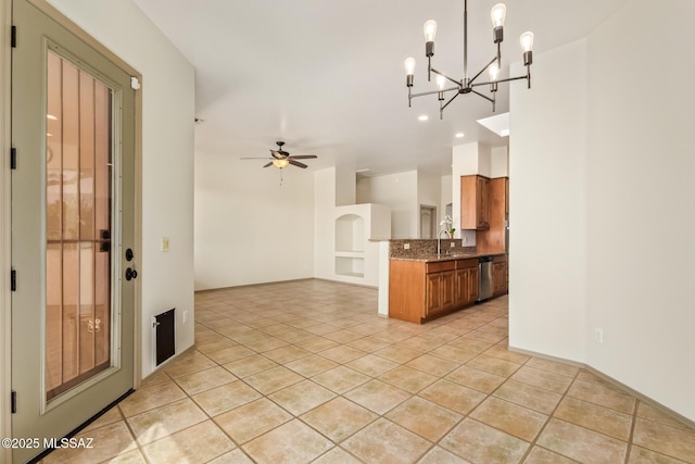 kitchen with brown cabinets, a sink, stainless steel dishwasher, dark stone counters, and light tile patterned flooring