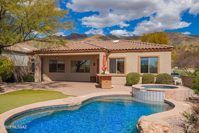 rear view of property featuring an outdoor pool, stucco siding, a patio area, a mountain view, and an in ground hot tub