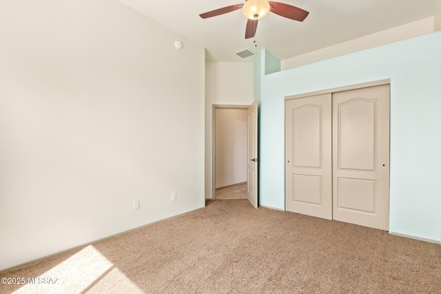 unfurnished bedroom with a closet, visible vents, light colored carpet, and a ceiling fan