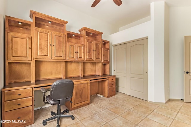 home office featuring light tile patterned flooring, built in desk, and a ceiling fan