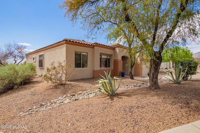 mediterranean / spanish home with a tiled roof, an attached garage, and stucco siding