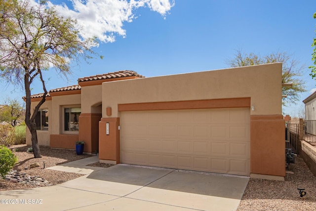 view of front facade with fence, a tiled roof, stucco siding, driveway, and an attached garage