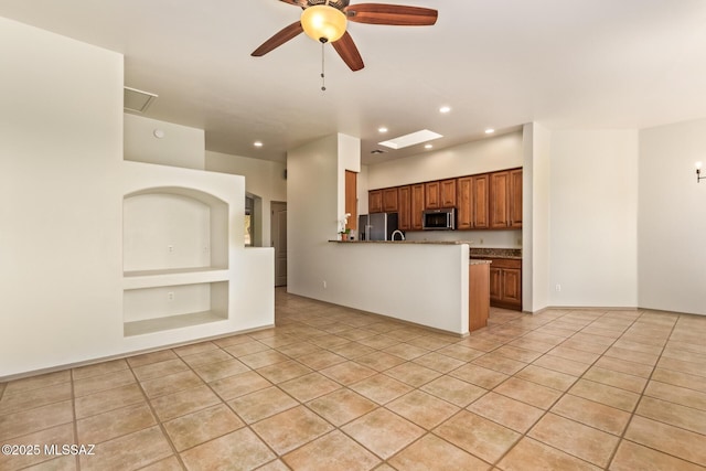 kitchen featuring stainless steel appliances, light tile patterned flooring, ceiling fan, and brown cabinetry